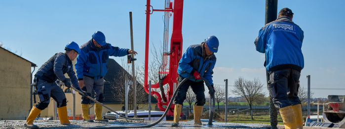 Bild von vier Beton- und Stahlbetonbauer, die auf einer Baustelle Beton gießen